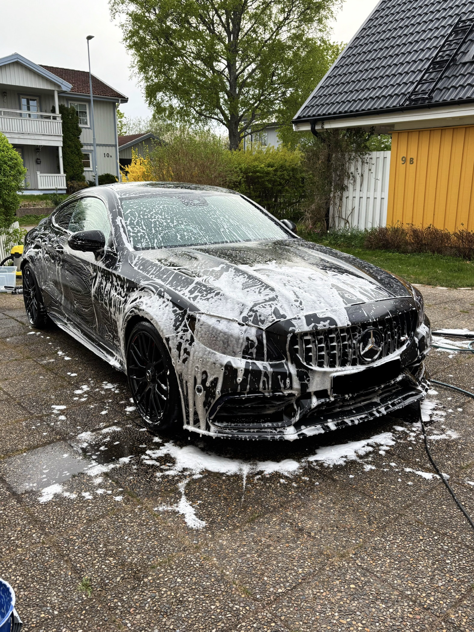 Mörkblå Volvo S90 täckt av skum under utvändig rekond i solsken